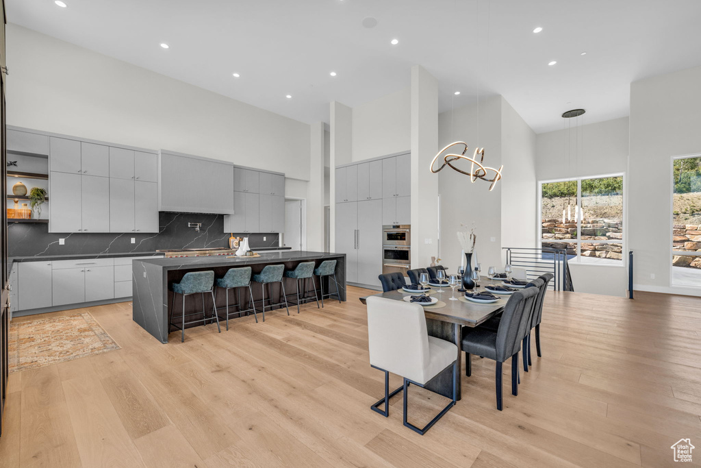 Dining area featuring an inviting chandelier, light wood-type flooring, and a high ceiling