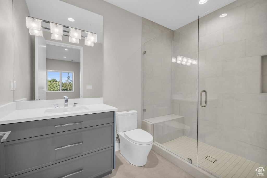 Bathroom with vanity, toilet, an enclosed shower, and tile patterned flooring