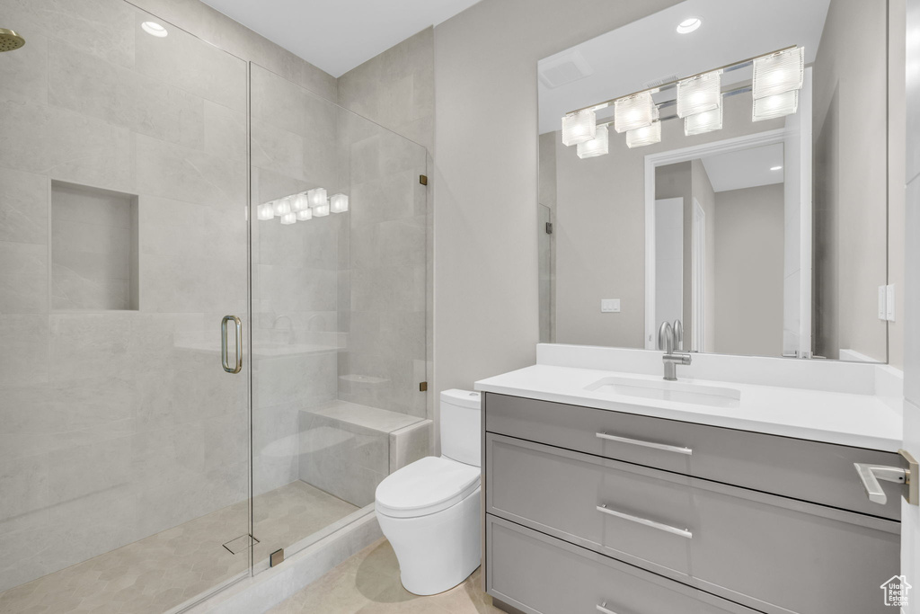 Bathroom featuring a shower with door, toilet, and vanity