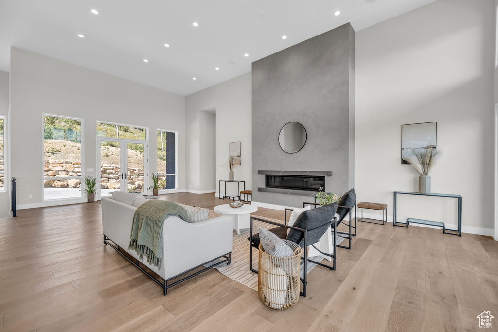 Living room featuring a high ceiling, a fireplace, and light wood-type flooring