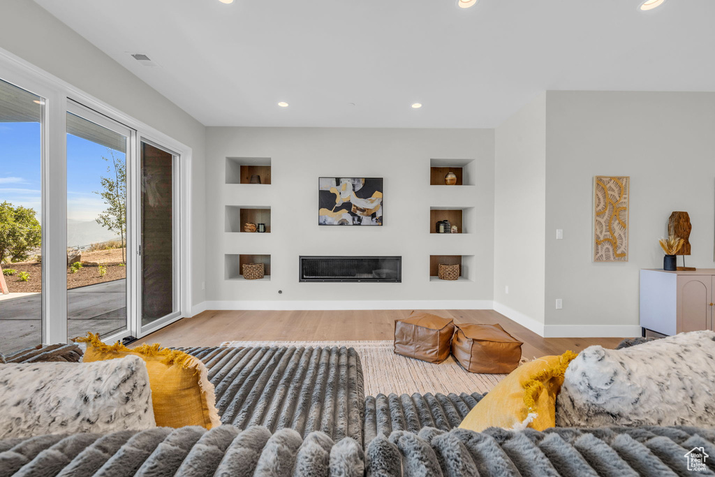 Living room with built in shelves and hardwood / wood-style flooring