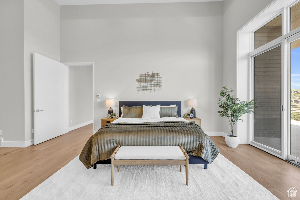 Bedroom with light wood-type flooring, access to exterior, and a high ceiling