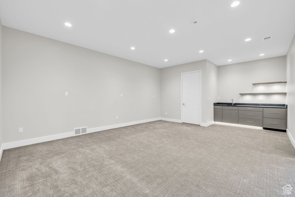 Unfurnished living room featuring sink and light carpet