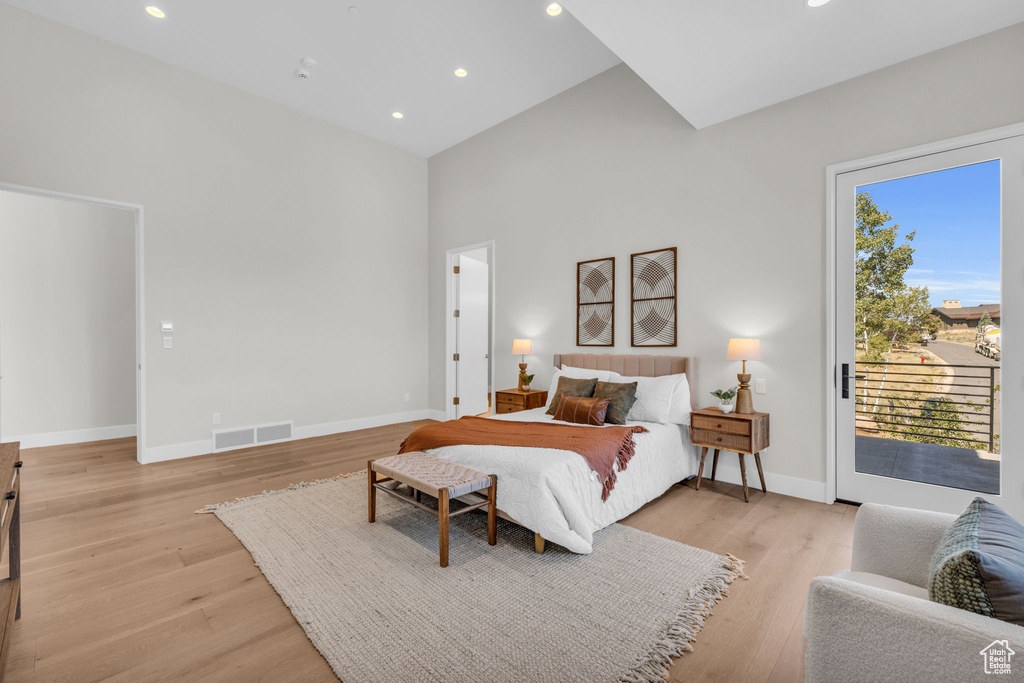 Bedroom featuring light hardwood / wood-style floors, access to outside, and high vaulted ceiling