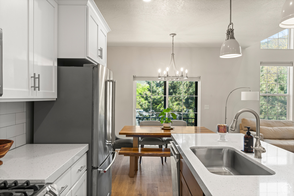 Kitchen with white cabinetry, hardwood / wood-style floors, pendant lighting, sink, and tasteful backsplash