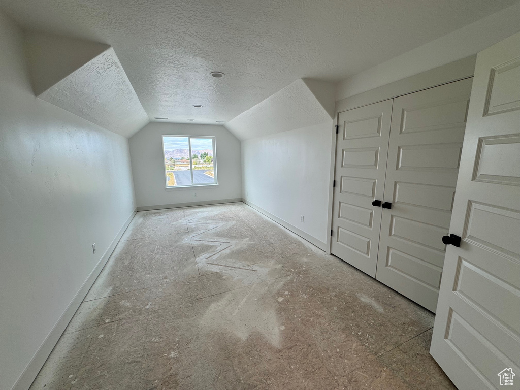 Bonus room with vaulted ceiling and a textured ceiling