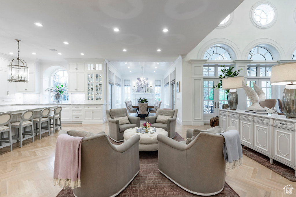 Living room with a notable chandelier, light parquet floors, and ornamental molding