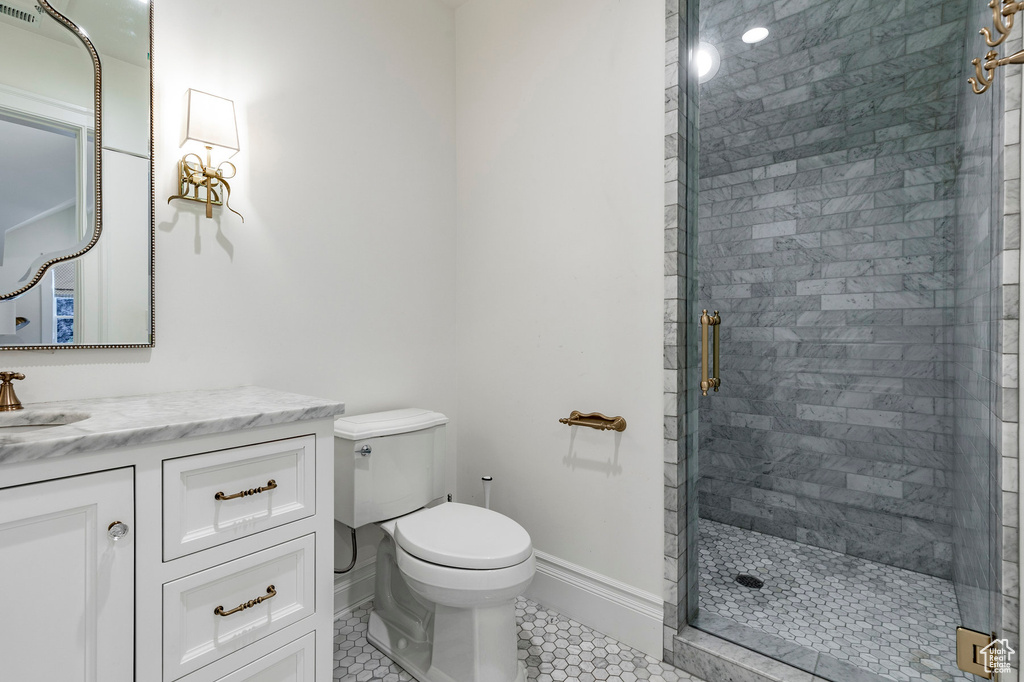 Bathroom with tile flooring, a shower with shower door, toilet, and vanity