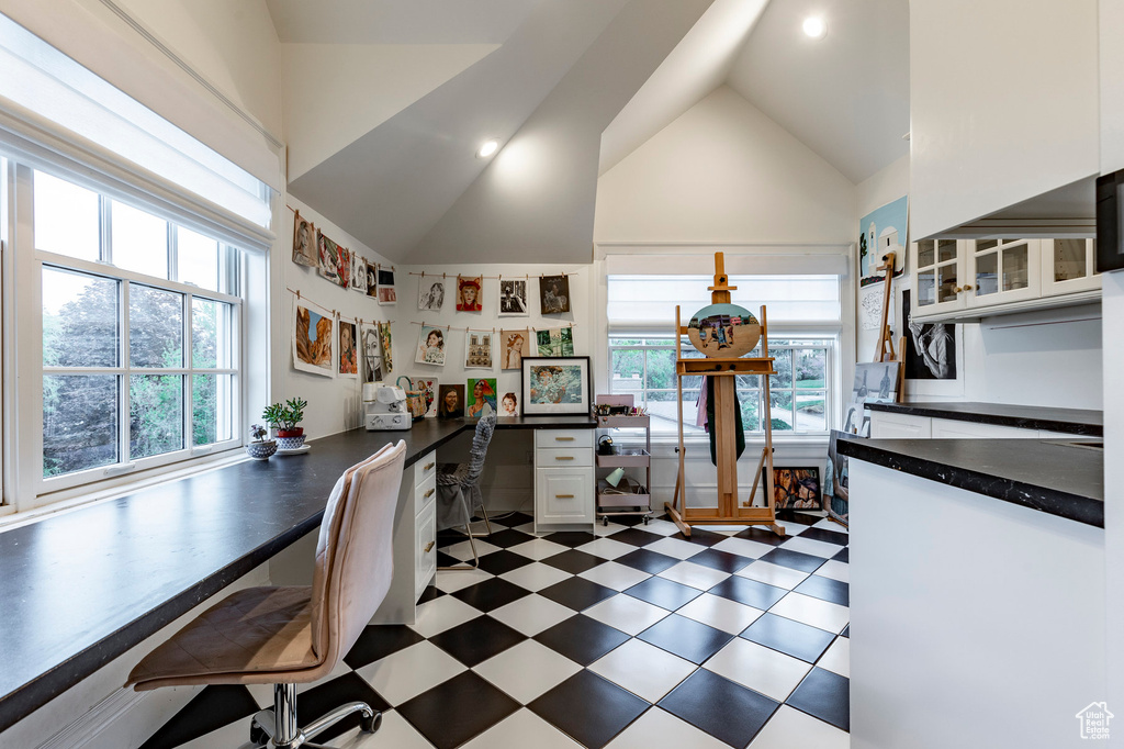 Kitchen with dark tile flooring, high vaulted ceiling, plenty of natural light, and white cabinetry