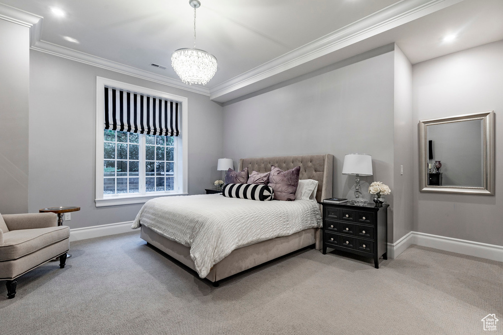 Carpeted bedroom with an inviting chandelier and ornamental molding