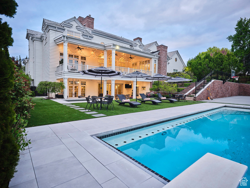 View of pool with a patio area, a lawn, and ceiling fan