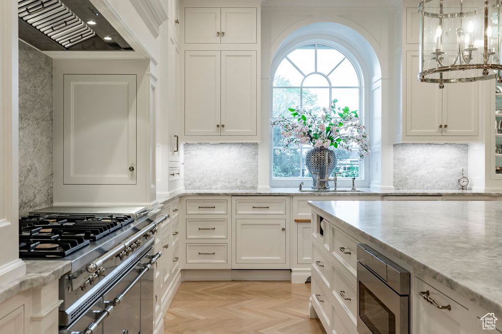 Kitchen featuring stainless steel microwave, a healthy amount of sunlight, light parquet flooring, and white cabinetry