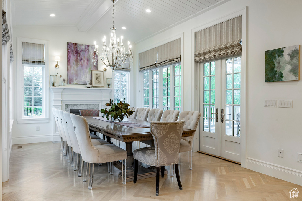 Dining area with a notable chandelier, lofted ceiling with beams, plenty of natural light, and light parquet flooring