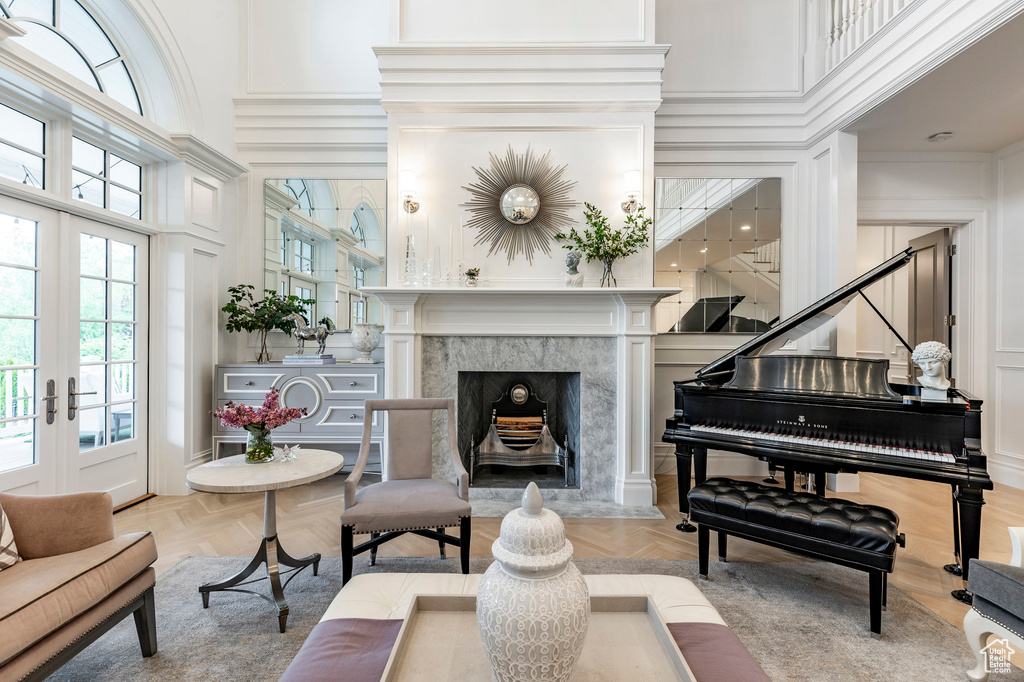 Interior space with a high ceiling, a premium fireplace, light parquet floors, and french doors