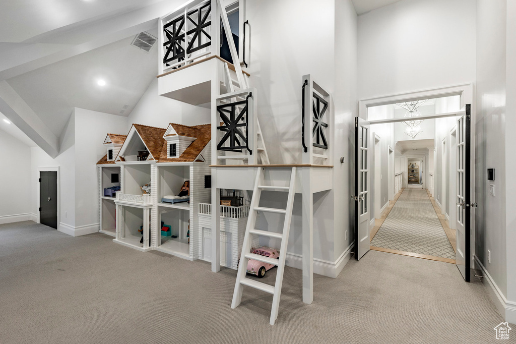 Hallway featuring high vaulted ceiling and light colored carpet