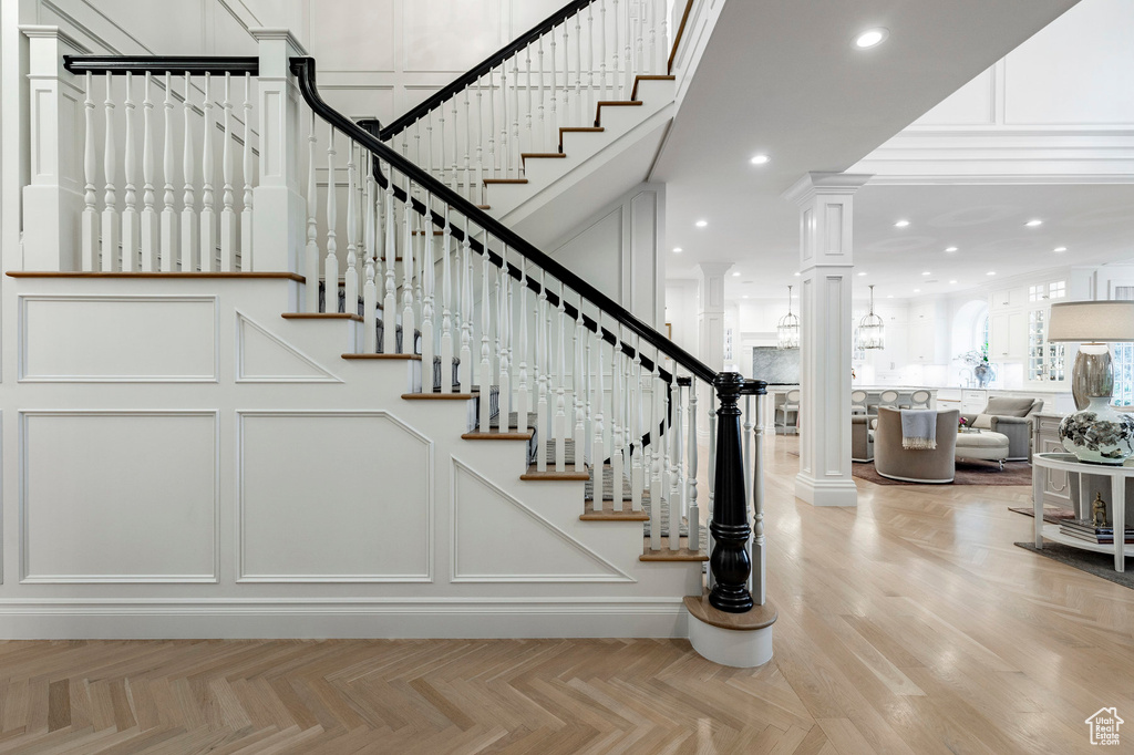 Stairs with ornate columns, a high ceiling, and light parquet flooring