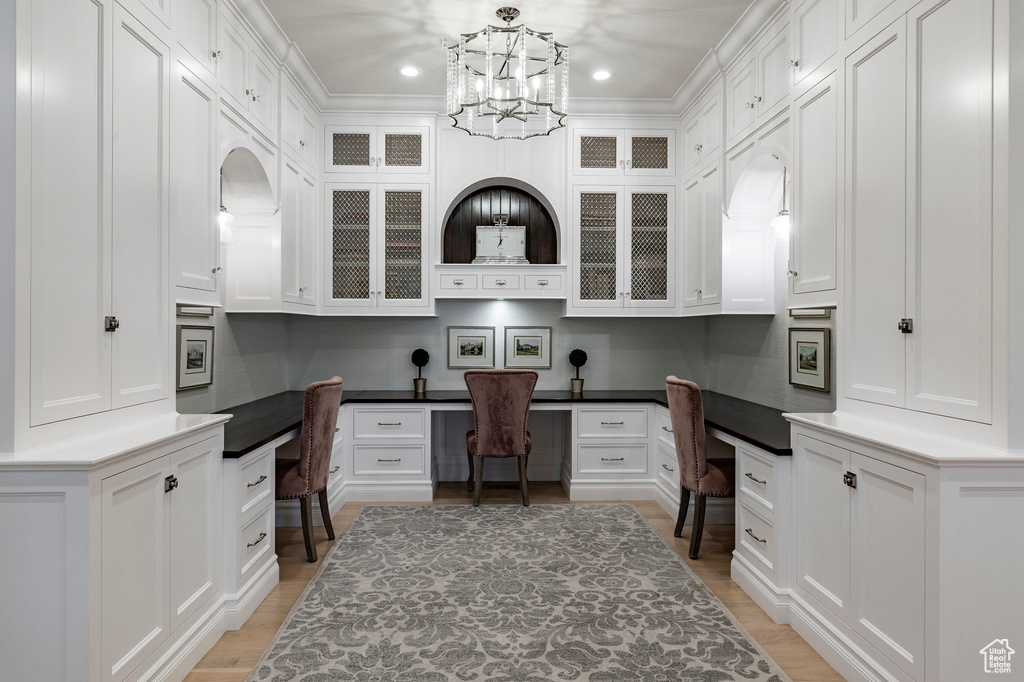 Office with built in desk, a chandelier, light wood-type flooring, and crown molding