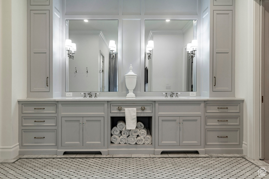 Bathroom featuring vanity with extensive cabinet space, double sink, and ornamental molding