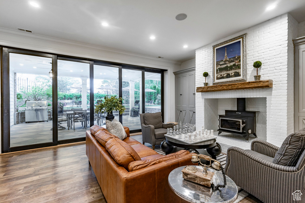 Living room with brick wall, wood-type flooring, plenty of natural light, and a wood stove