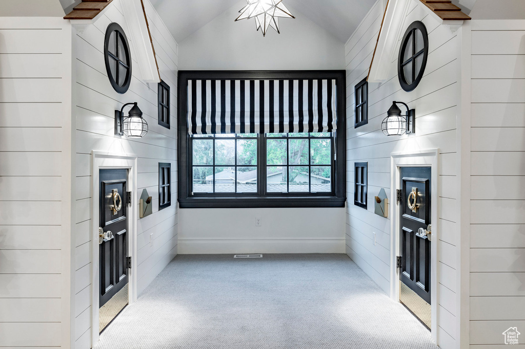 Unfurnished living room featuring light carpet and lofted ceiling