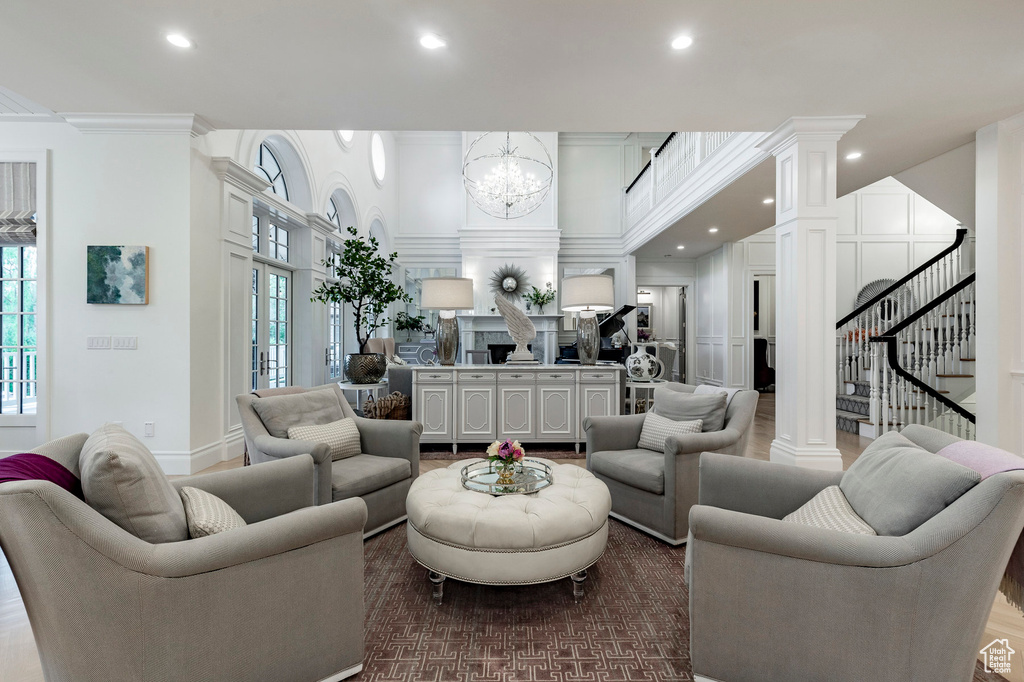 Living room with a notable chandelier, decorative columns, and crown molding