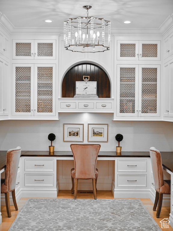 Office with built in desk, ornamental molding, light hardwood / wood-style floors, and an inviting chandelier