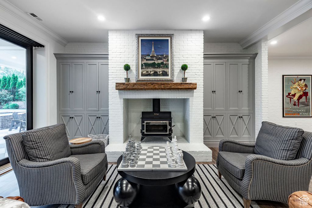 Living room with ornamental molding, light wood-type flooring, a wood stove, and brick wall