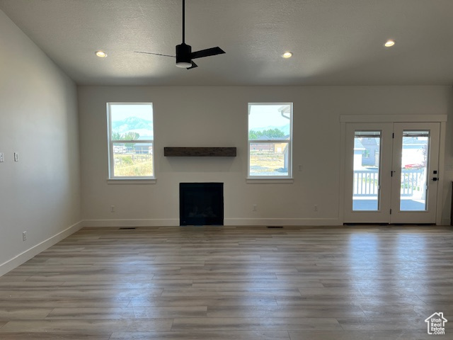 Unfurnished living room featuring light wood-type flooring, a wealth of natural light, and ceiling fan