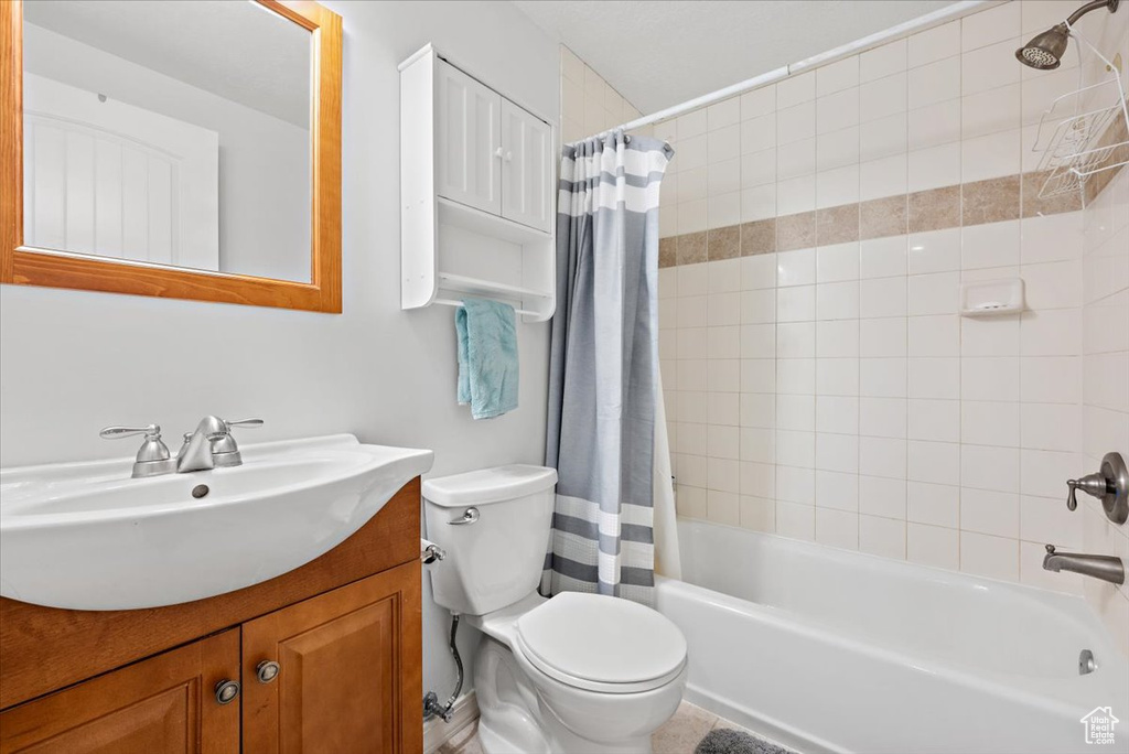 Full bathroom featuring shower / tub combo, toilet, and large vanity