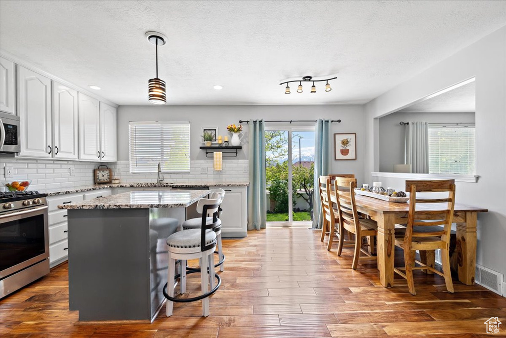 Kitchen featuring a center island, stainless steel appliances, tasteful backsplash, and white cabinetry