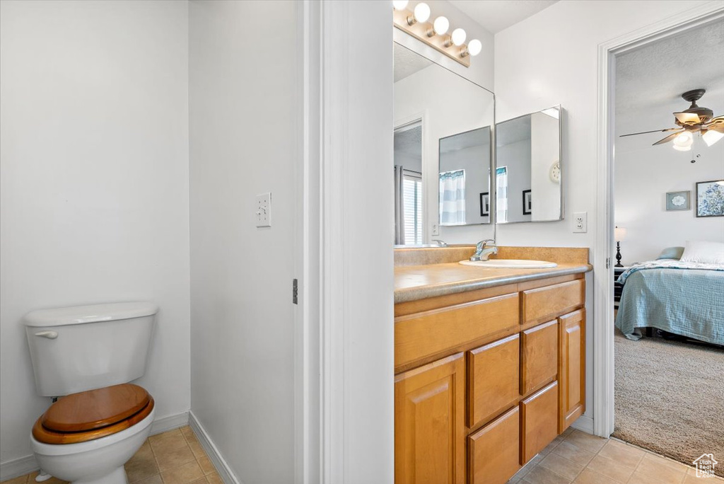 Bathroom with tile floors, large vanity, ceiling fan, and toilet