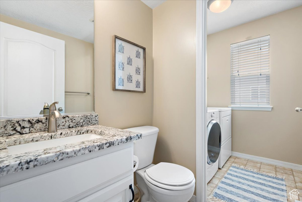 Bathroom with tile flooring, oversized vanity, toilet, and washing machine and dryer