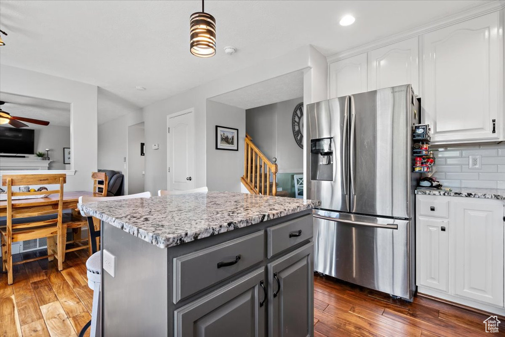 Kitchen featuring stainless steel fridge, a kitchen island, dark hardwood / wood-style flooring, white cabinets, and tasteful backsplash