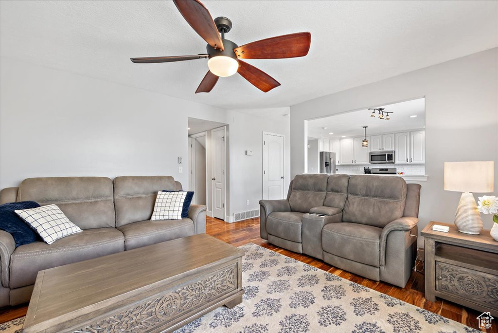 Living room with ceiling fan and hardwood / wood-style floors