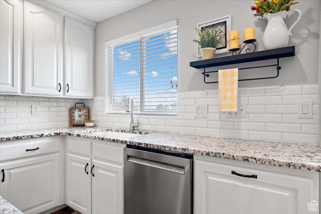 Kitchen with dishwasher, backsplash, sink, a healthy amount of sunlight, and white cabinets