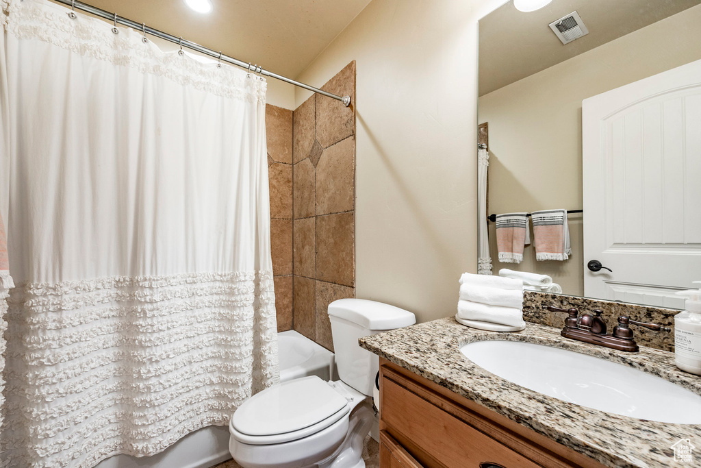 Full bathroom featuring toilet, shower / bath combo with shower curtain, and large vanity