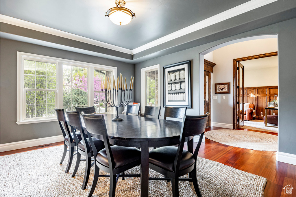 Dining room featuring a healthy amount of sunlight, ornamental molding, and hardwood / wood-style flooring