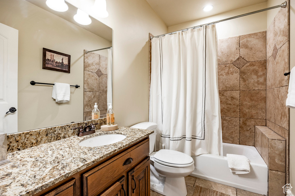 Full bathroom with tile floors, vanity, toilet, and shower / bath combo with shower curtain