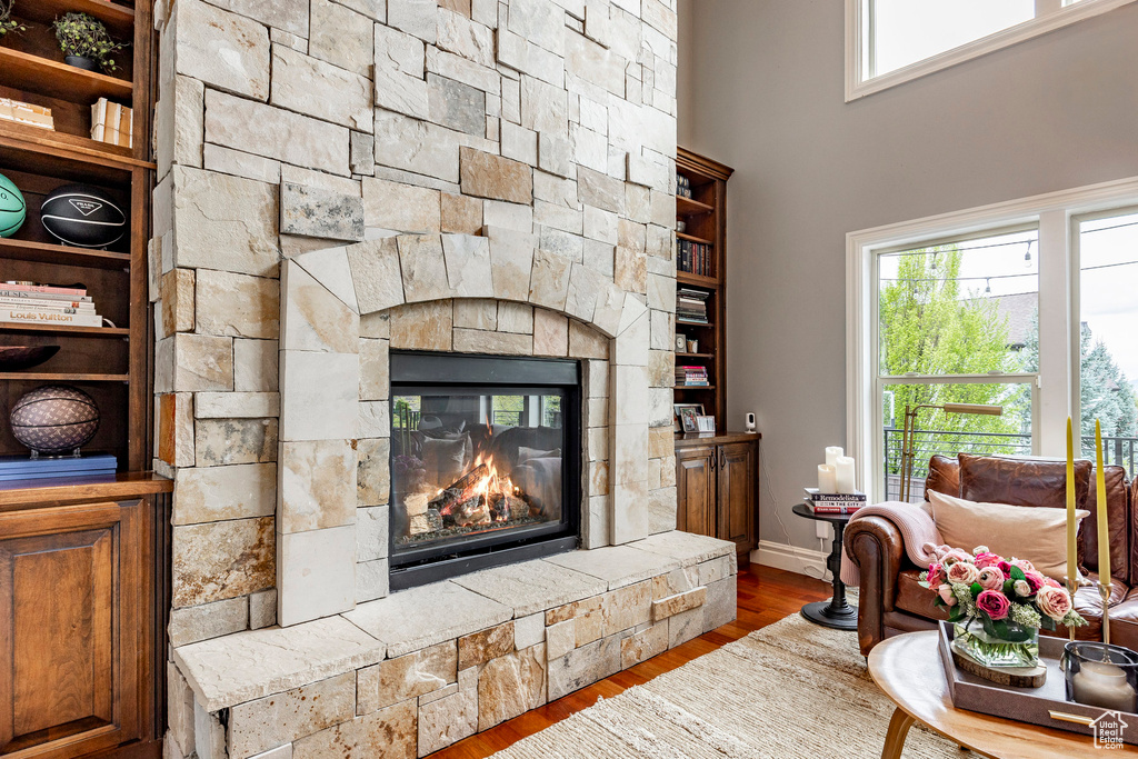 Living room featuring a stone fireplace, a healthy amount of sunlight, and wood-type flooring