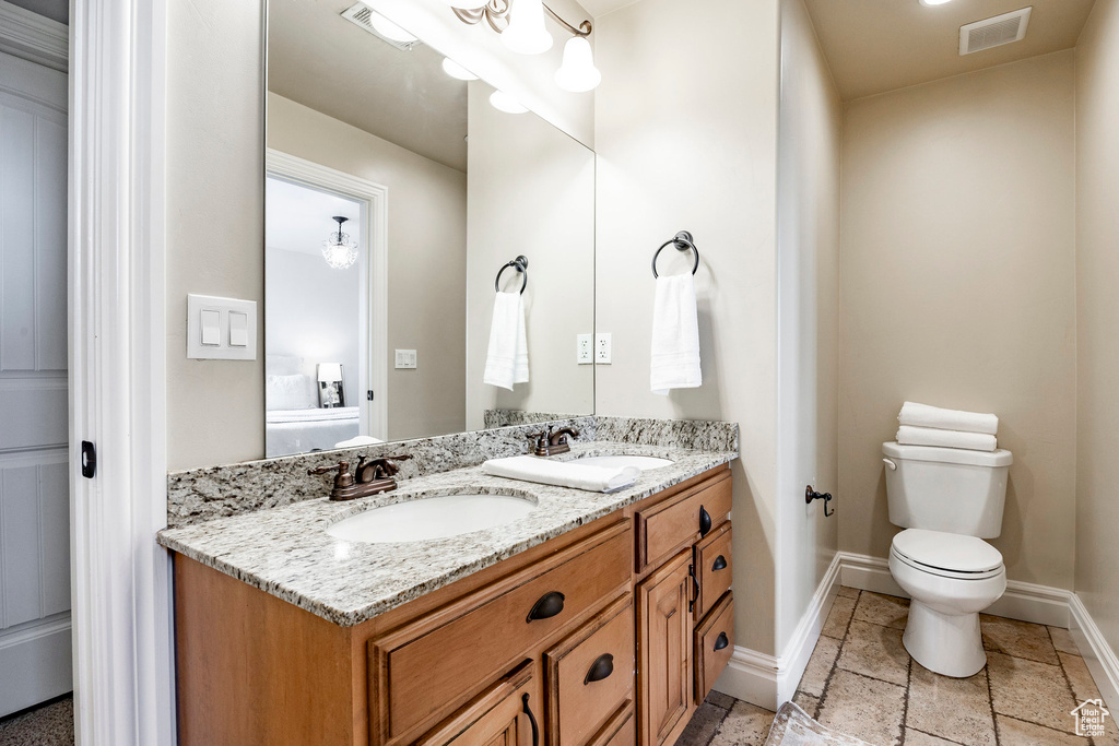 Bathroom featuring tile floors, double sink, toilet, and large vanity