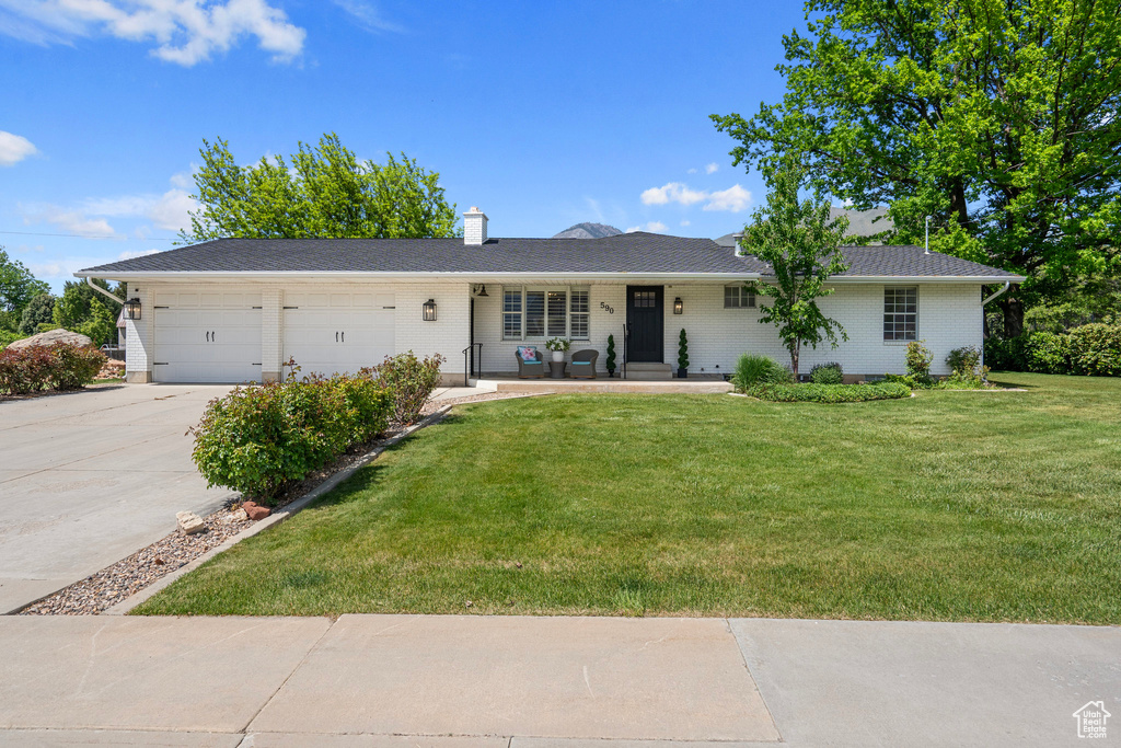 Single story home with a garage and a front lawn