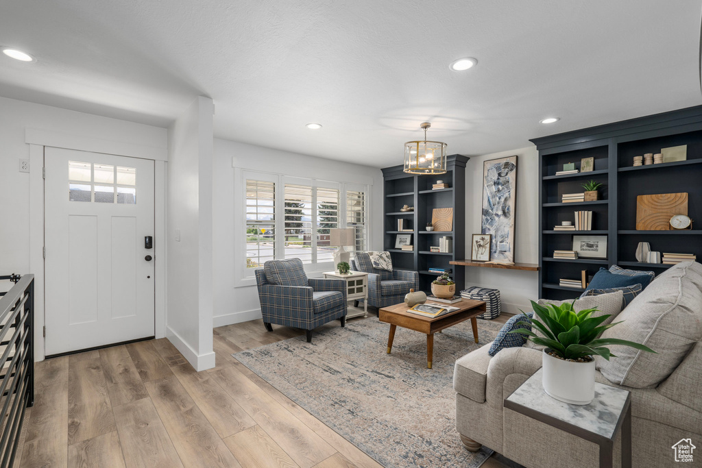 Living room featuring built in shelves, a chandelier, and hardwood / wood-style flooring