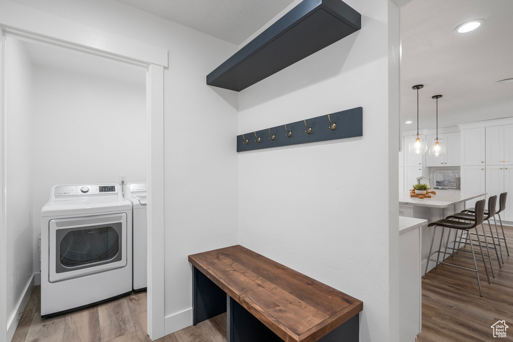 Laundry area with washer and clothes dryer and light wood-type flooring