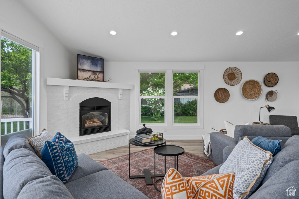 Living room featuring a healthy amount of sunlight, wood-type flooring, and a brick fireplace