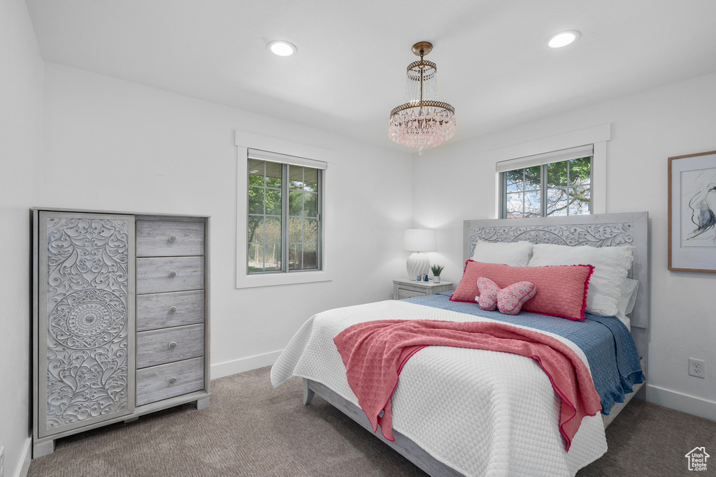 Carpeted bedroom with a chandelier and multiple windows