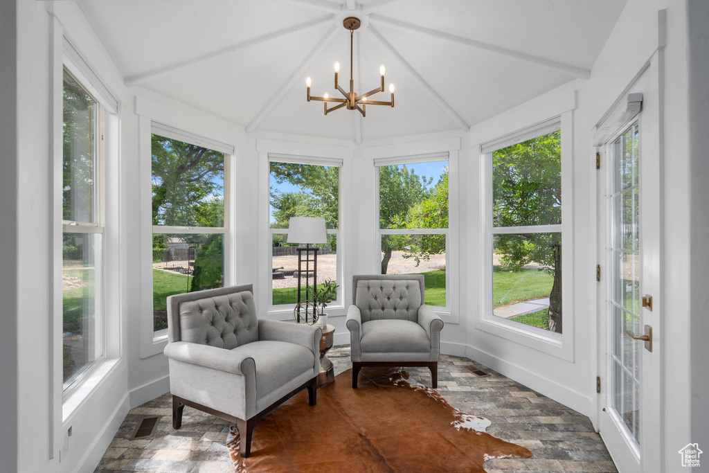 Sunroom with a wealth of natural light, a notable chandelier, and lofted ceiling