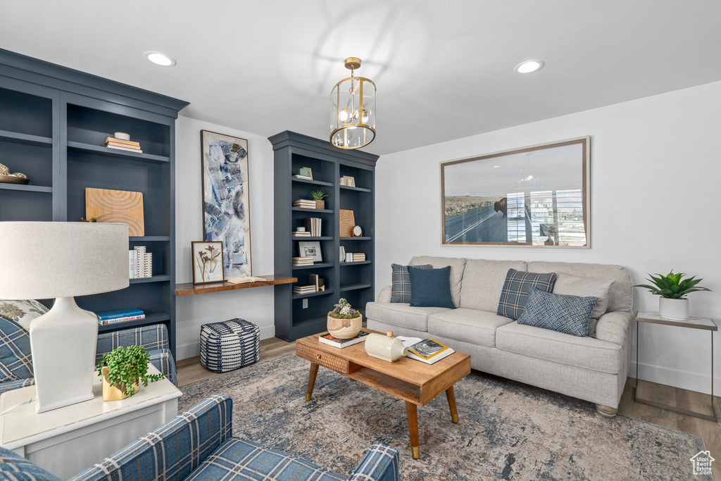 Living room with wood-type flooring, built in shelves, and a chandelier