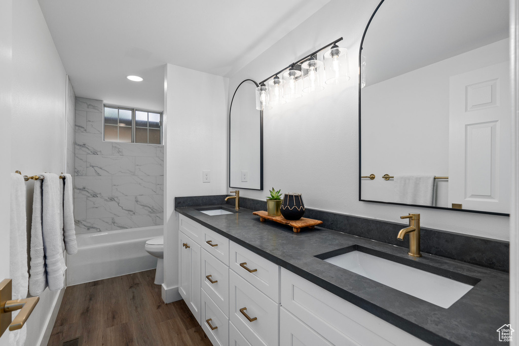 Full bathroom featuring dual vanity, hardwood / wood-style floors, toilet, and tiled shower / bath combo