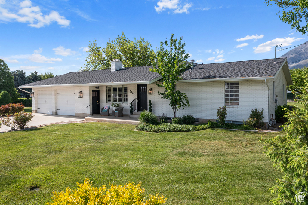 Ranch-style home featuring a front yard and a garage