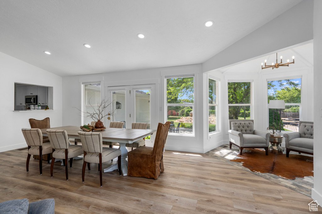 Dining space with a notable chandelier, lofted ceiling, and light hardwood / wood-style flooring